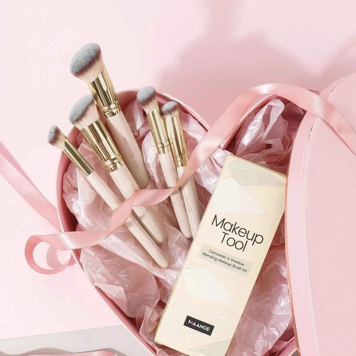 Apricot-coloured angled blush brush and four other synthetic makeup brushes on a white background