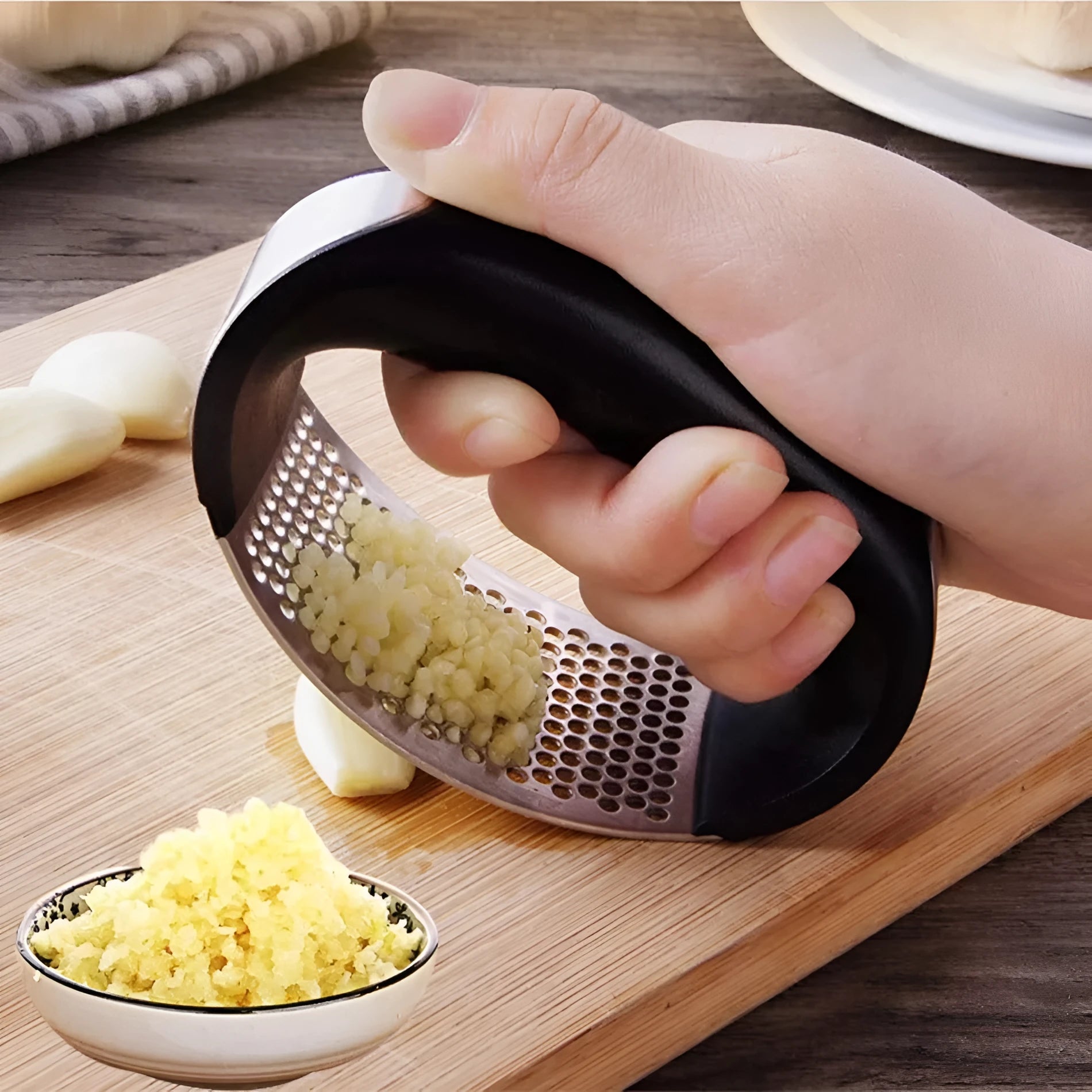 Stainless steel garlic press with ergonomic handle in assorted colours on a kitchen worktop.