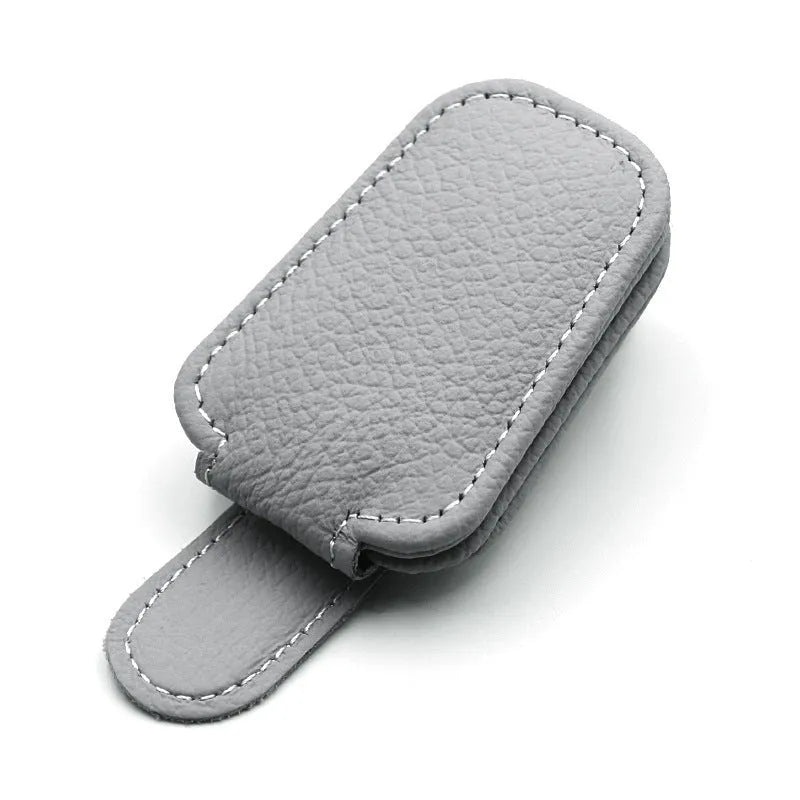 Car sunglasses holder clip with PU leather case attached to a sun visor.