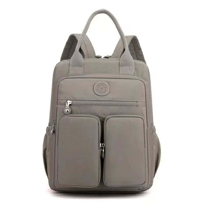 Women's waterproof nylon travel backpack in grey, showing front external pocket and organisational interior.