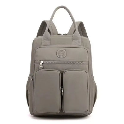 Women's waterproof nylon travel backpack in grey, showing front external pocket and organisational interior.
