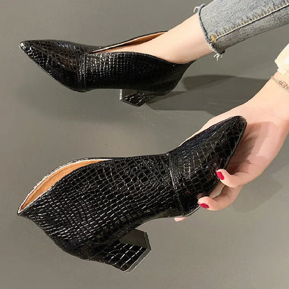 Women's black V cut Martin boots with a pointed embossed toe and a chunky heel.