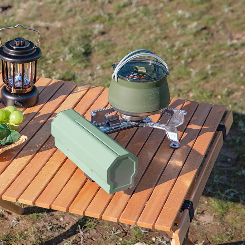 Green folding camping gas stove with serrated pot bracket, showing 25cm size next to butane canister
