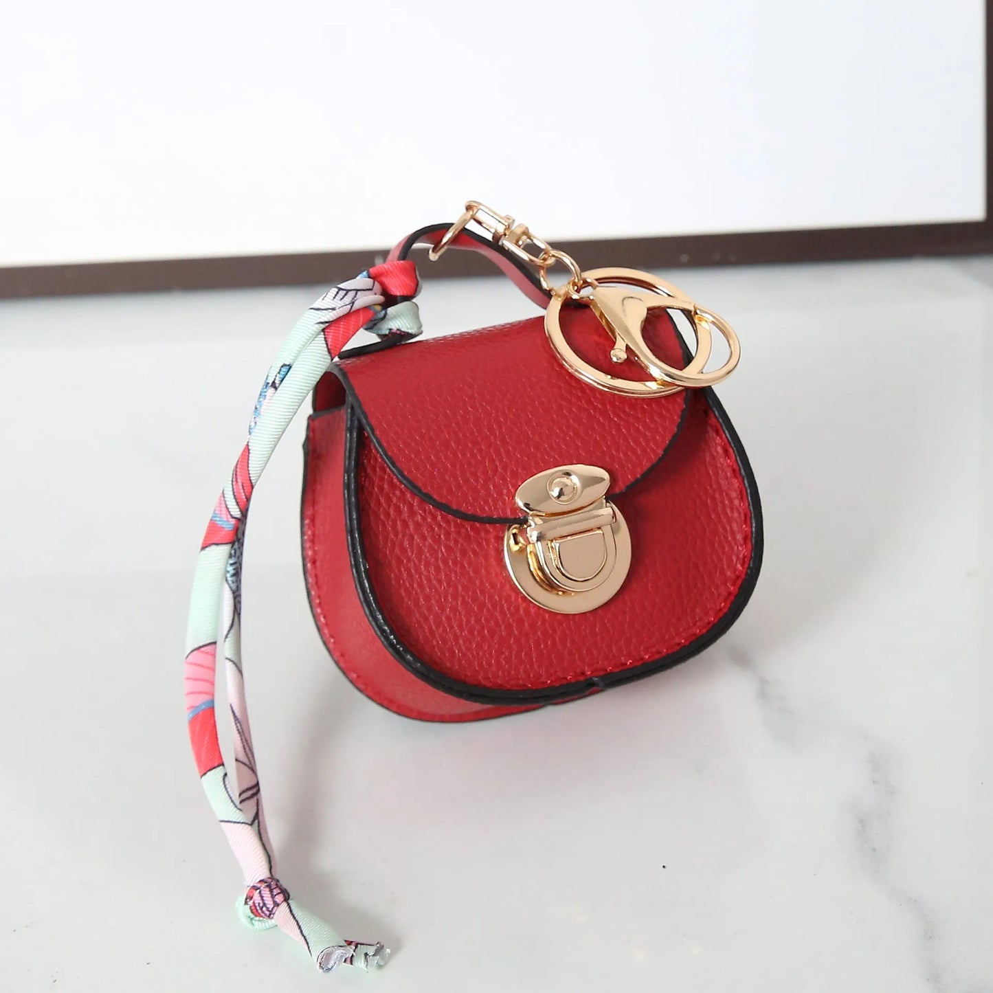 Solid colour PVC coin purse keychain shown in saddle bag black, orange, brown, red, grey, and pink.