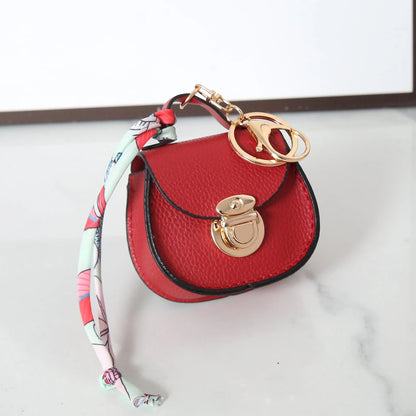 Solid colour PVC coin purse keychain shown in saddle bag black, orange, brown, red, grey, and pink.