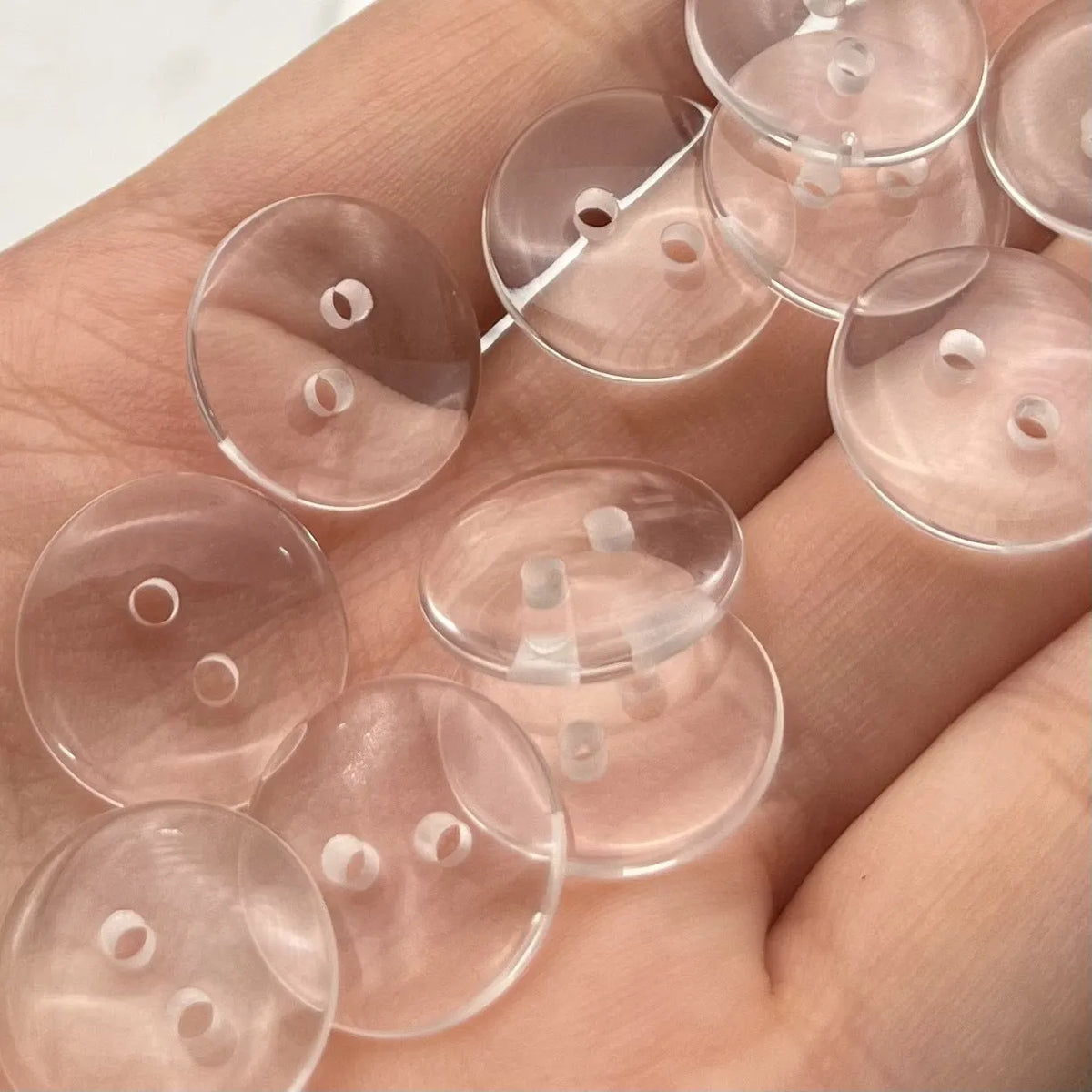Transparent plastic resin sewing buttons with two holes, 10mm in diameter.