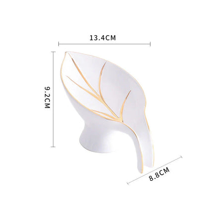 A ceramic soap dish with a sleek leaf-shaped design, featuring a suction cup base for secure and tidy placement in the bathroom or kitchen.