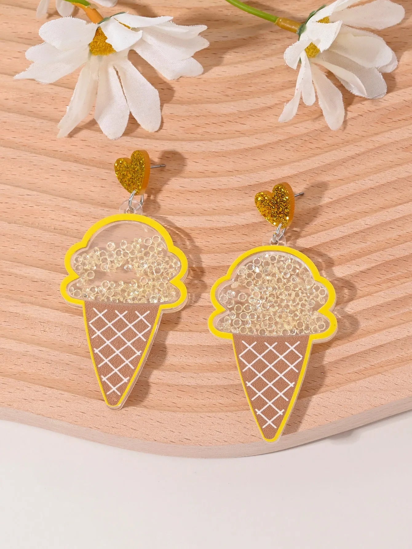 A pair of colourful acrylic earrings shaped like a strawberry and a cherry on a woman's ear.