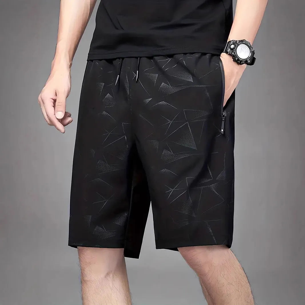 Man wearing loose-fit grey printed sports shorts with elastic waistband, showcasing the above-knee length.