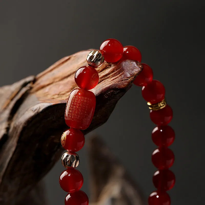 A red agate beaded bracelet with a Guanyin pendant on a white background.