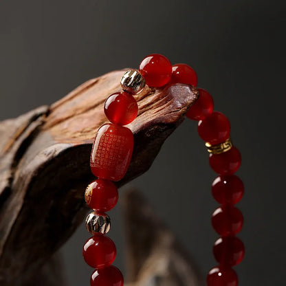 A red agate beaded bracelet with a Guanyin pendant on a white background.