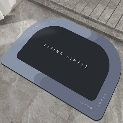 Oval grey bath mat with non-slip rubber bottom on a tiled floor, showing absorbent fabric surface