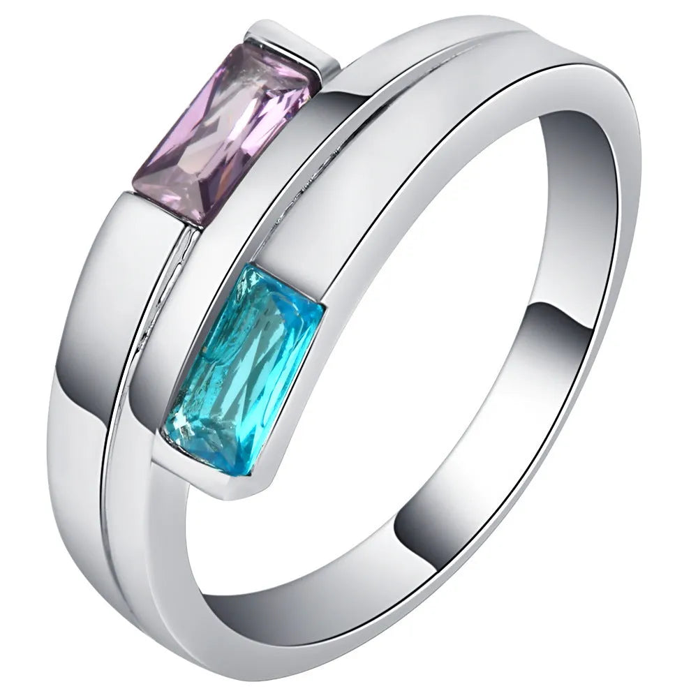 Silver coloured copper electroplated ring with a central zircon stone, shown on a finger.