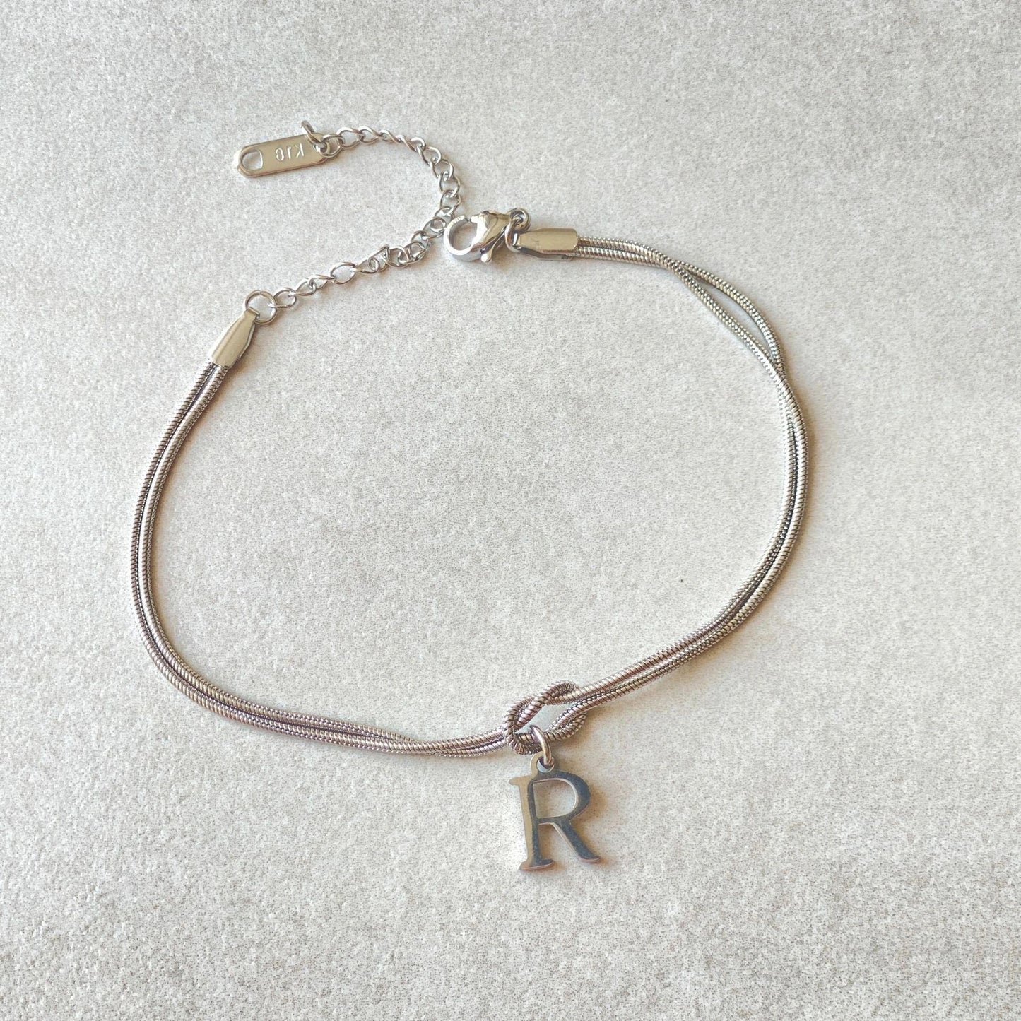 Elegant letter charm bracelets for women in gold and silver tones, featuring a delicate snake chain design and personalised letter charms.