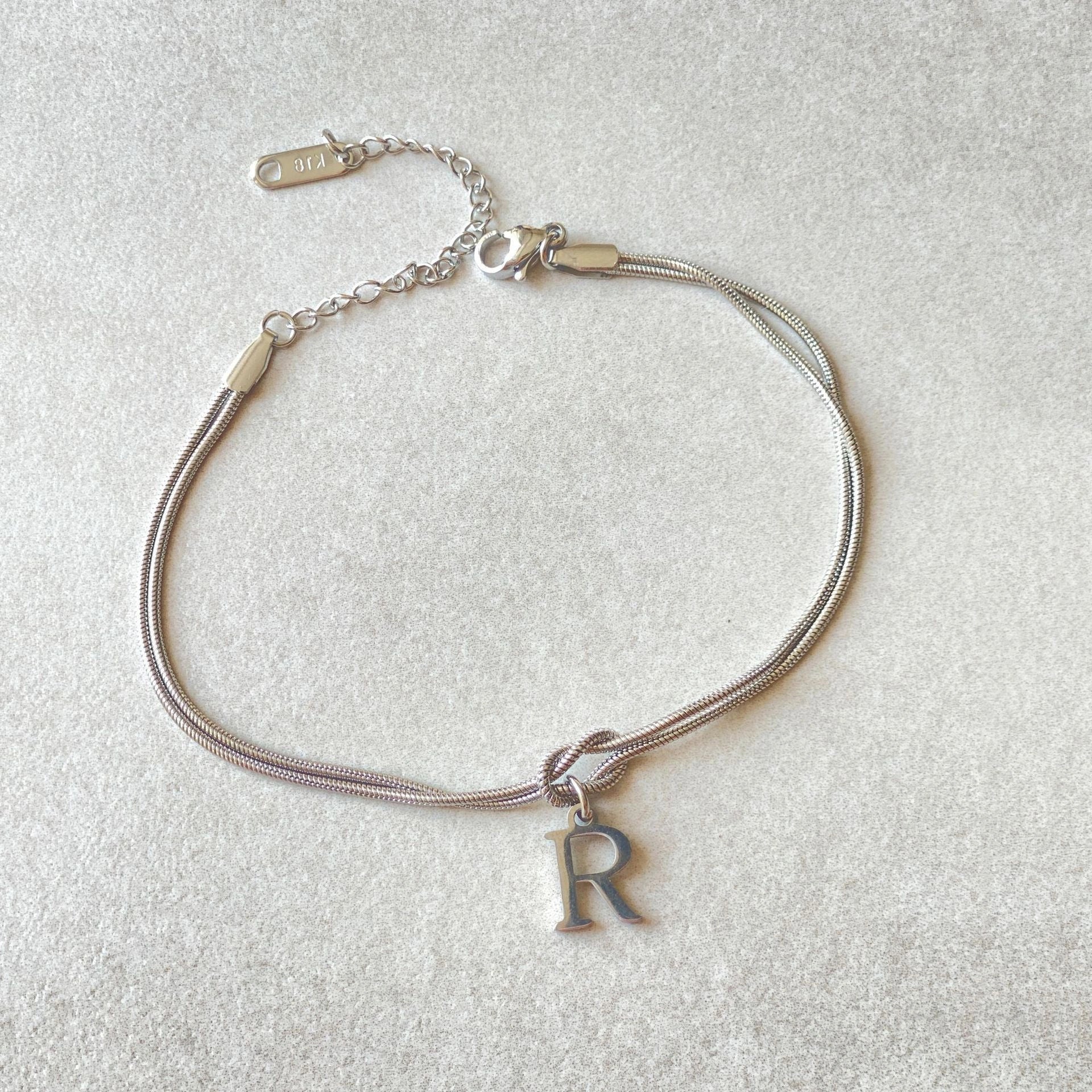 Elegant letter charm bracelets for women in gold and silver tones, featuring a delicate snake chain design and personalised letter charms.