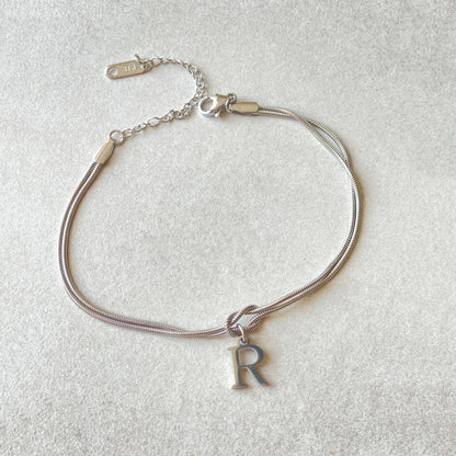 Elegant letter charm bracelets for women in gold and silver tones, featuring a delicate snake chain design and personalised letter charms.
