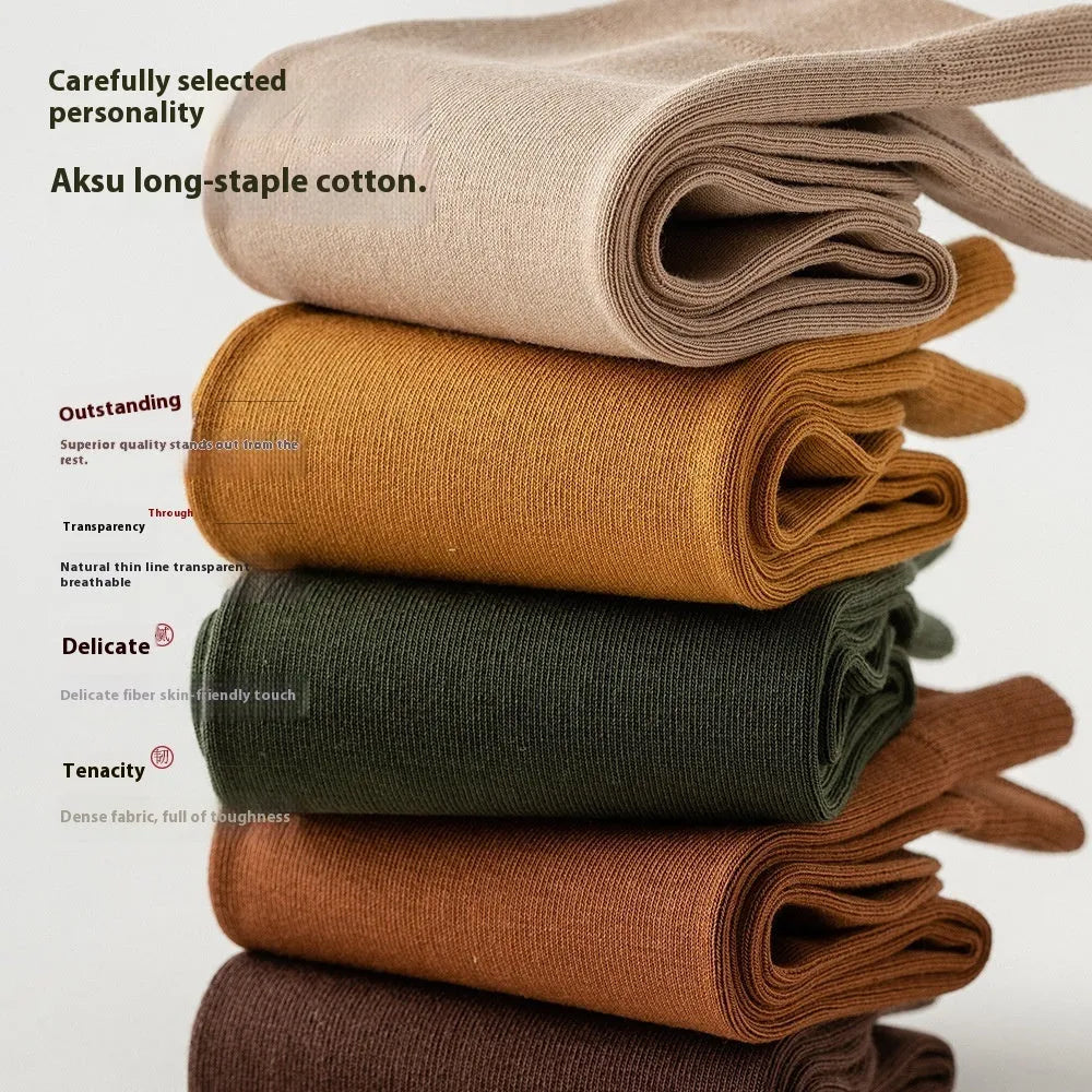 Pair of solid-colour men's mid-calf socks made from combed cotton on a wooden background