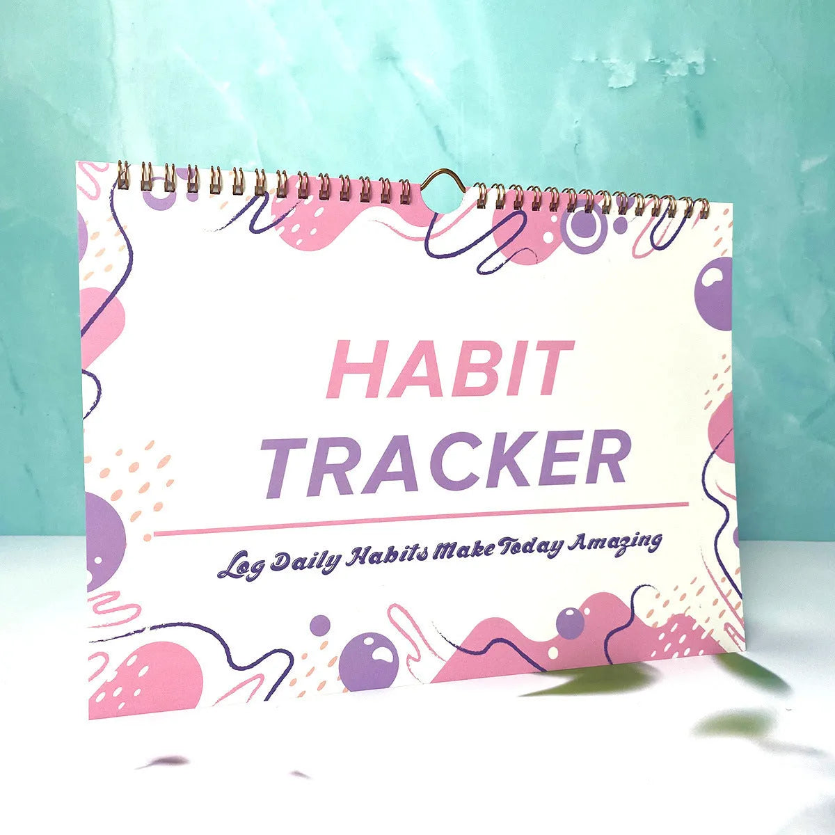 Habit tracking planner book open showing 12 internal pages, measuring 21cm by 28cm.