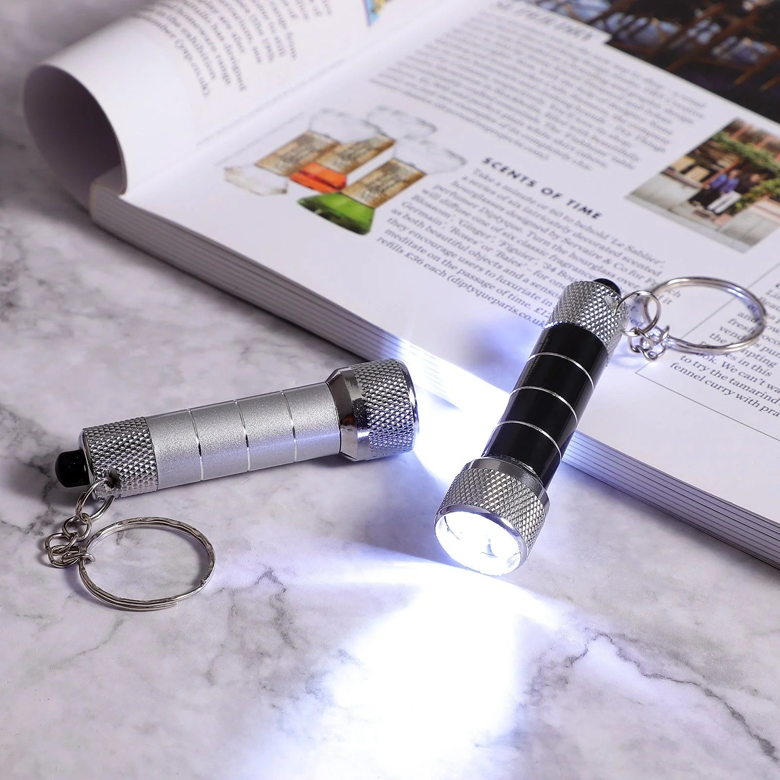 Compact aluminium LED keychain torch in four colours: white, black, red, and blue.