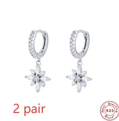 A pair of geometric snowflake pendant earrings in sterling silver with cubic zirconia stones, on a white background.