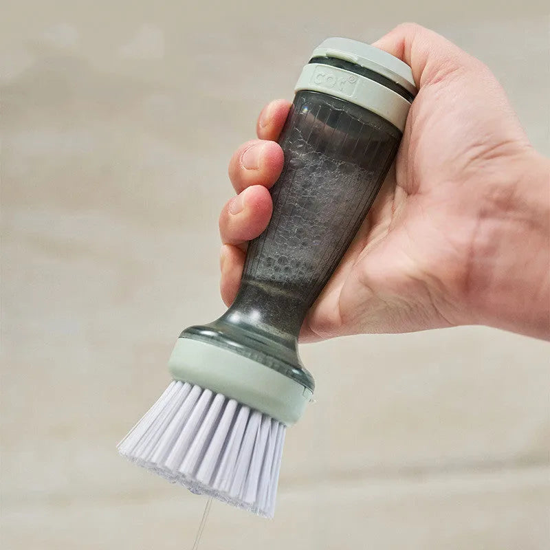 Milk white and mint green pot scrub brush with a soap dispenser handle and replaceable non-scratch bristles.