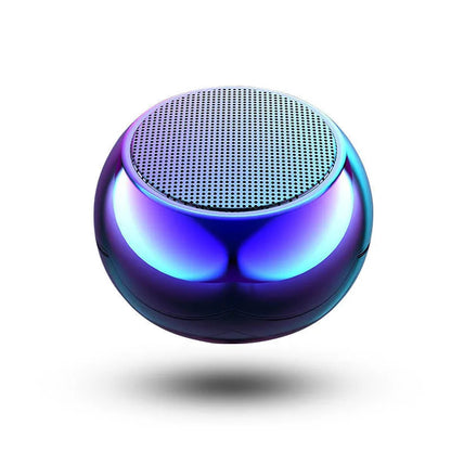 Small round aluminium Bluetooth speaker in gradient blue, showing compact size next to a USB cable.