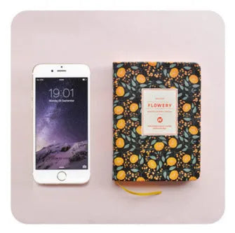 Green floral notepad with fabric imitation leather cover lying open on a table.