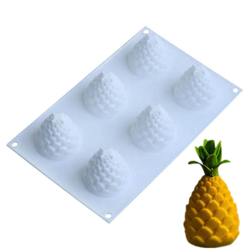 Flexible blue silicone baking mould with six cavities shaped like pineapples and pine cones on a kitchen counter.