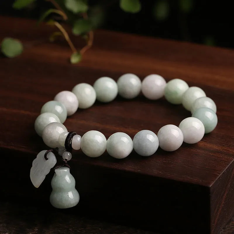Natural green jade charm bracelet with carved apple and geometric stone pendants.