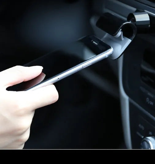 Black universal car phone holder with 360-degree rotation mounted on a car air vent, holding a mobile phone.