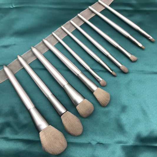 10 makeup brushes with moonlight silver finish and wooden handles beside PU brush bag