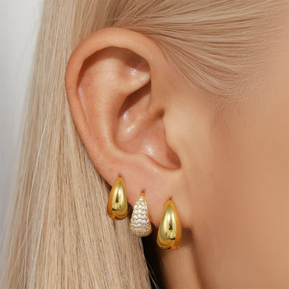 Pair of golden geometric clip-on earrings with a round design and screw-back mechanism on a white background.