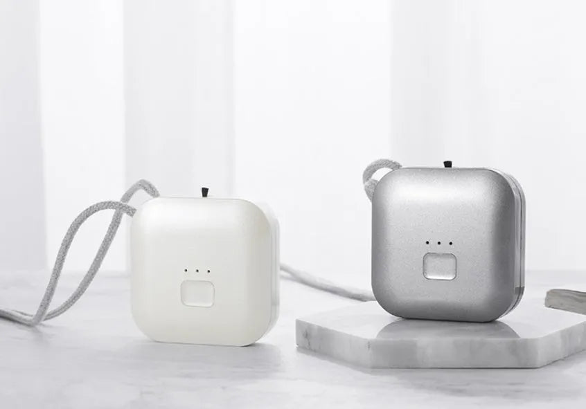 Compact pink USB air purifier necklace on a table with charging cable, showing dimensions 1.5 by 5.7 cm.