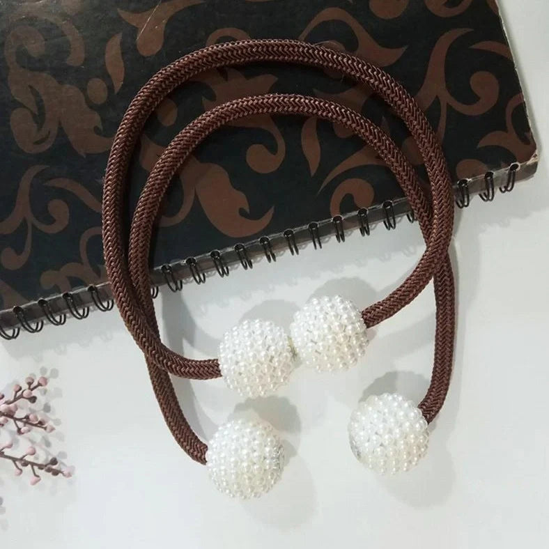 Magnetic curtain tiebacks with white pearl beads and fabric loops holding gathered curtain