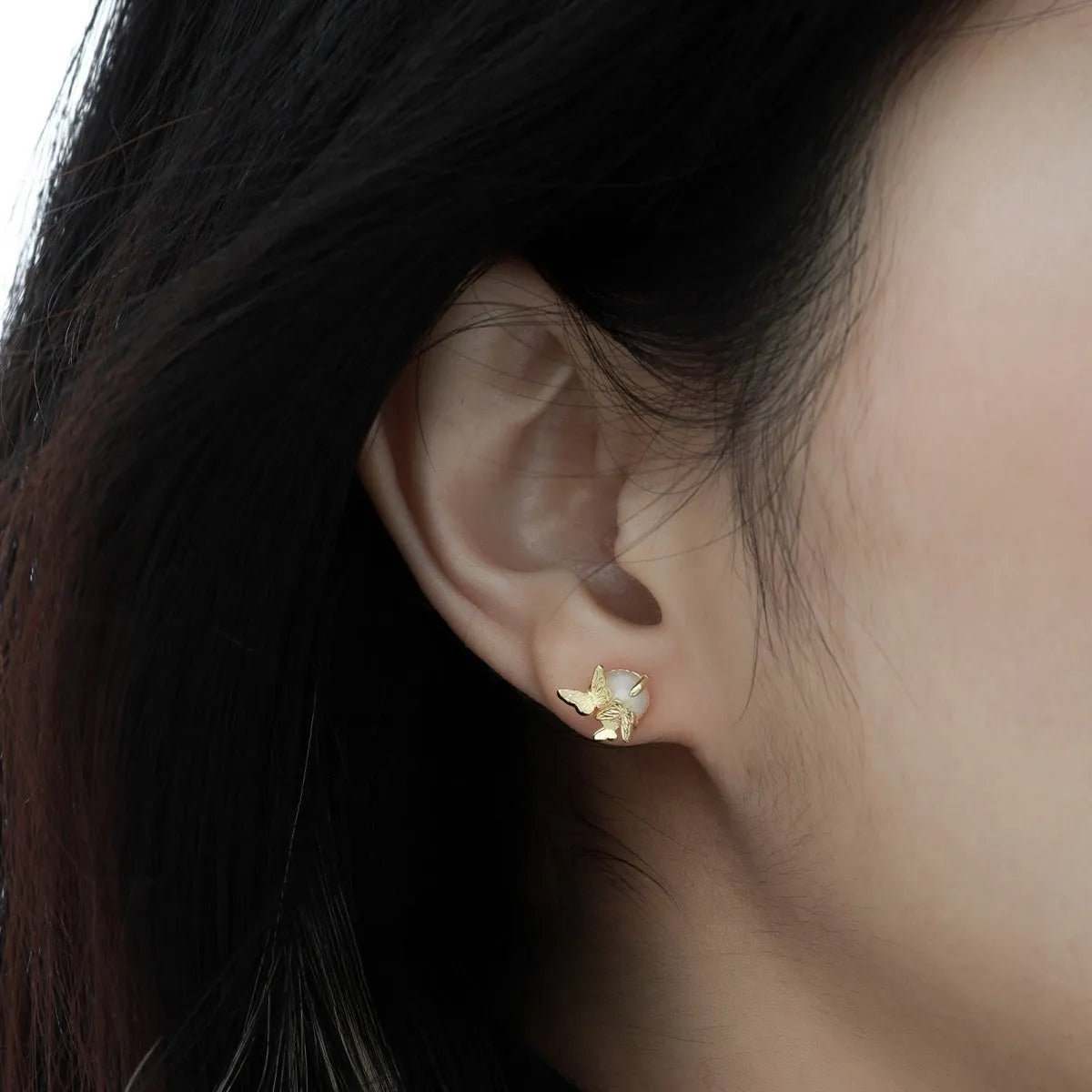 Close-up of a pair of 925 silver butterfly ear studs with gold plating, showing detailed animal zodiac modelling.
