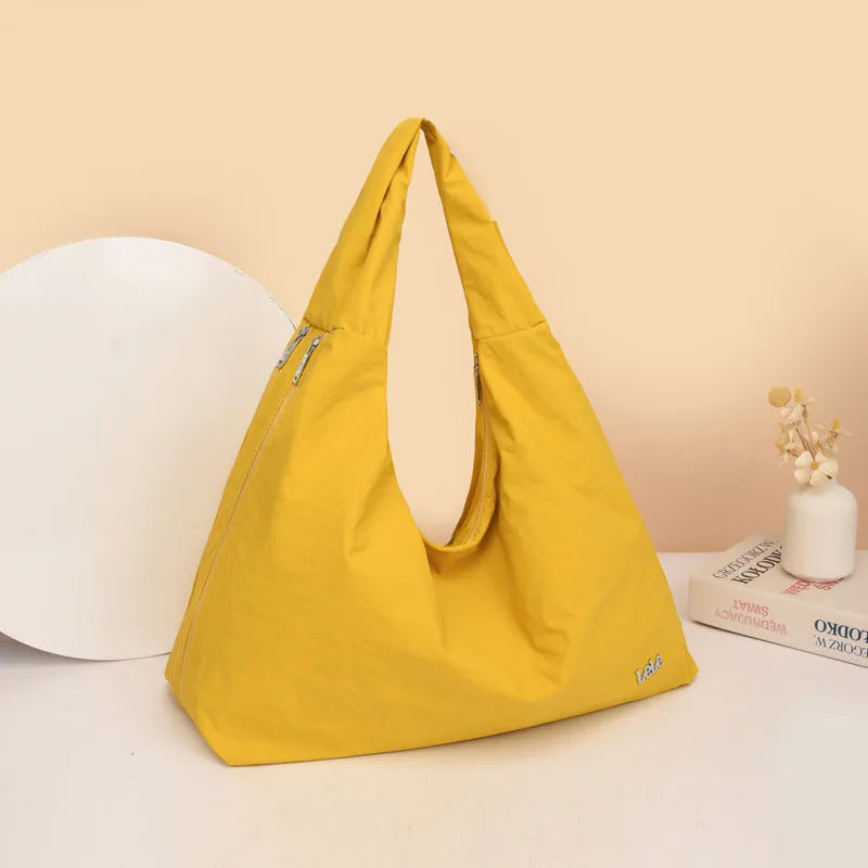 A soft nylon underarm bag with a heart-shaped design in blue, shown worn crossbody.