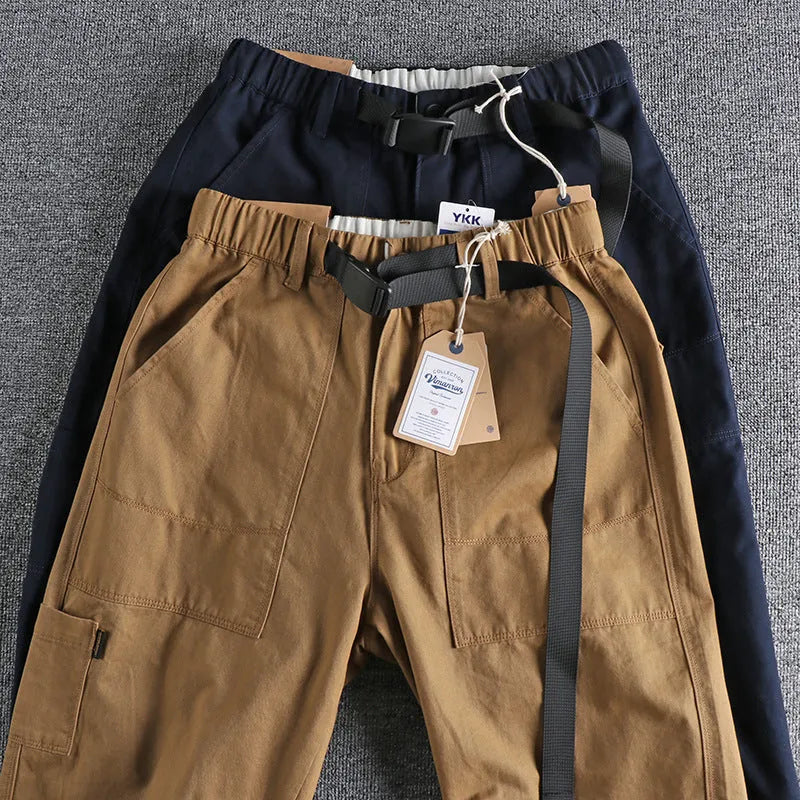 Men's khaki work trousers with a three-dimensional cut and an N I buckle belt on a hanger.