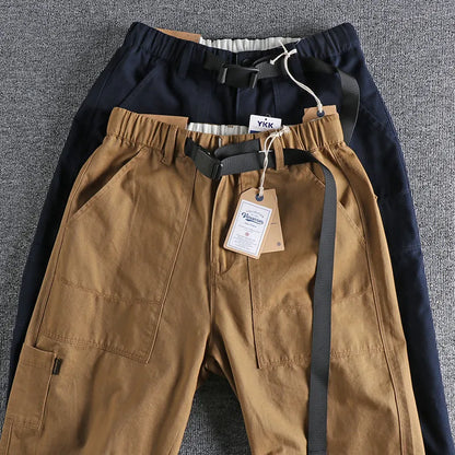 Men's khaki work trousers with a three-dimensional cut and an N I buckle belt on a hanger.