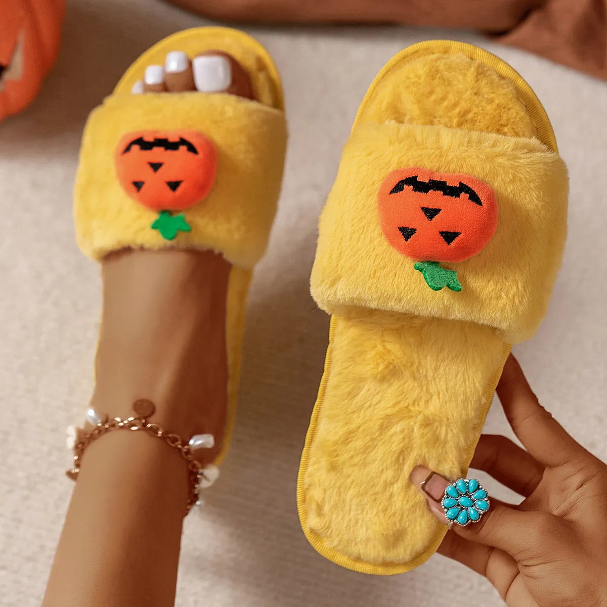 Yellow and white Halloween pumpkin cartoon plush slippers with synthetic fur and textured PVC anti-slip sole.