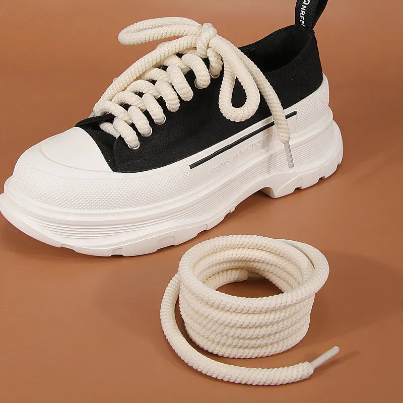 Round woven white, beige, and black shoelaces for bread shoes showing different lengths on a flat surface.