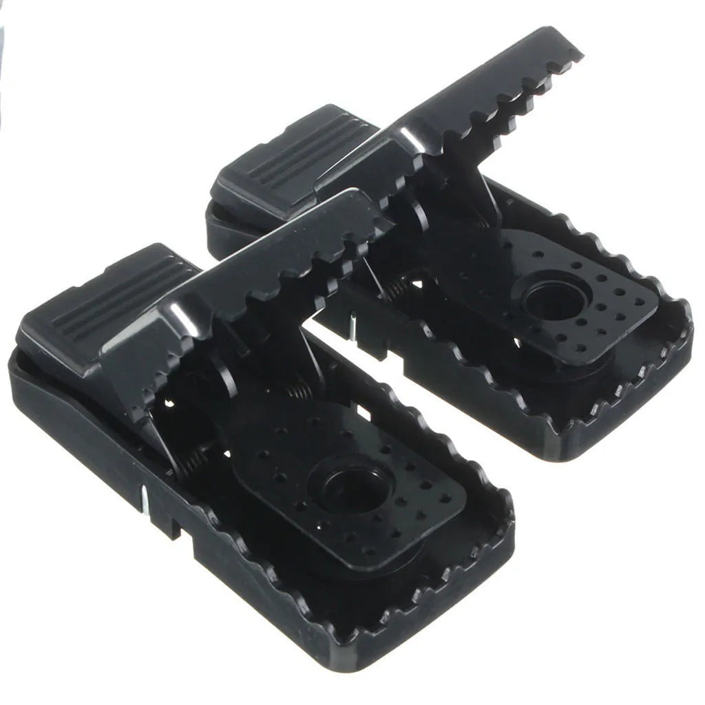 Six black plastic snapping mousetraps laid out on a surface, showing their size and smooth construction.