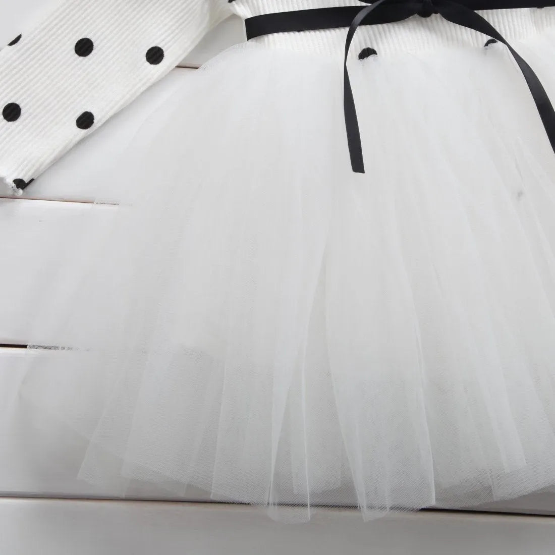 Baby girl wearing a long sleeve black tutu dress with lace detail for a birthday party.