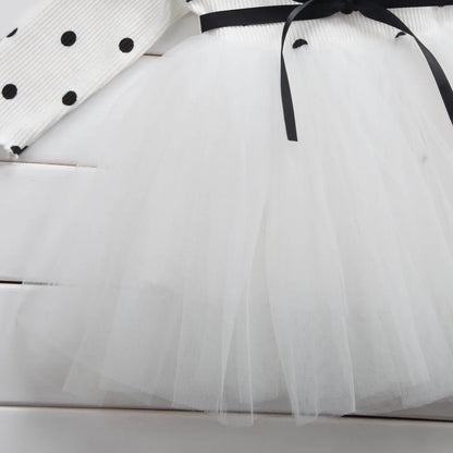Baby girl wearing a long sleeve black tutu dress with lace detail for a birthday party.