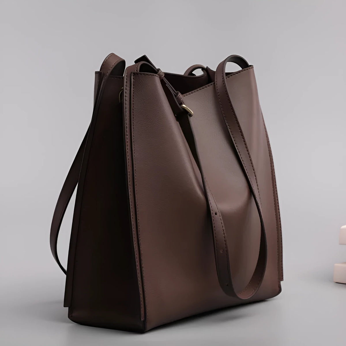 Brown genuine leather women's bucket-style commuter bag with double shoulder straps showing internal compartments
