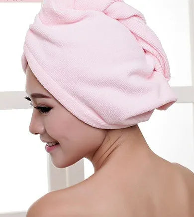 A woman wearing a sky blue microfiber hair dryer cap, with wet hair tucked inside, showing the towel's wrap-around design.