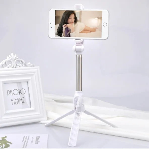 Black aluminium phone tripod stand with extended legs and a Bluetooth remote, holding an iPhone.