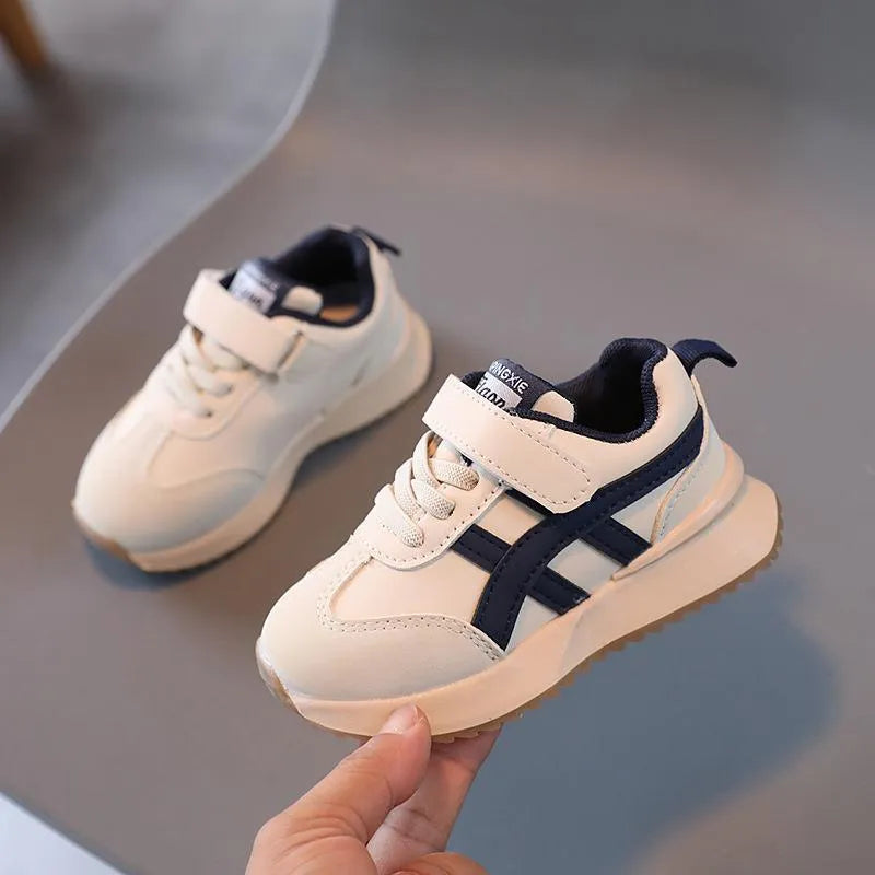 Children's white synthetic leather sneaker with Velcro strap on a non-slip rubber sole.