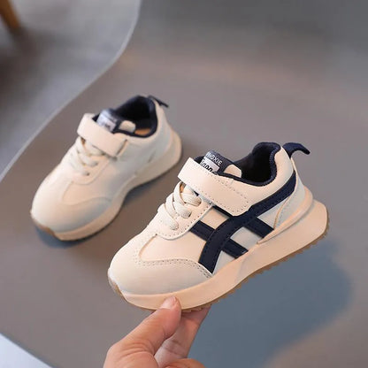 Children's white synthetic leather sneaker with Velcro strap on a non-slip rubber sole.