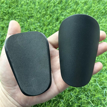 Extra small 8x5cm black and white plastic football shin guards for junior players.