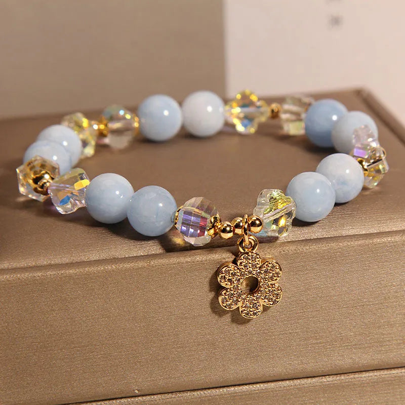 Women's aquamarine crystal bracelet with four-leaf clover charm and pearl details on wrist